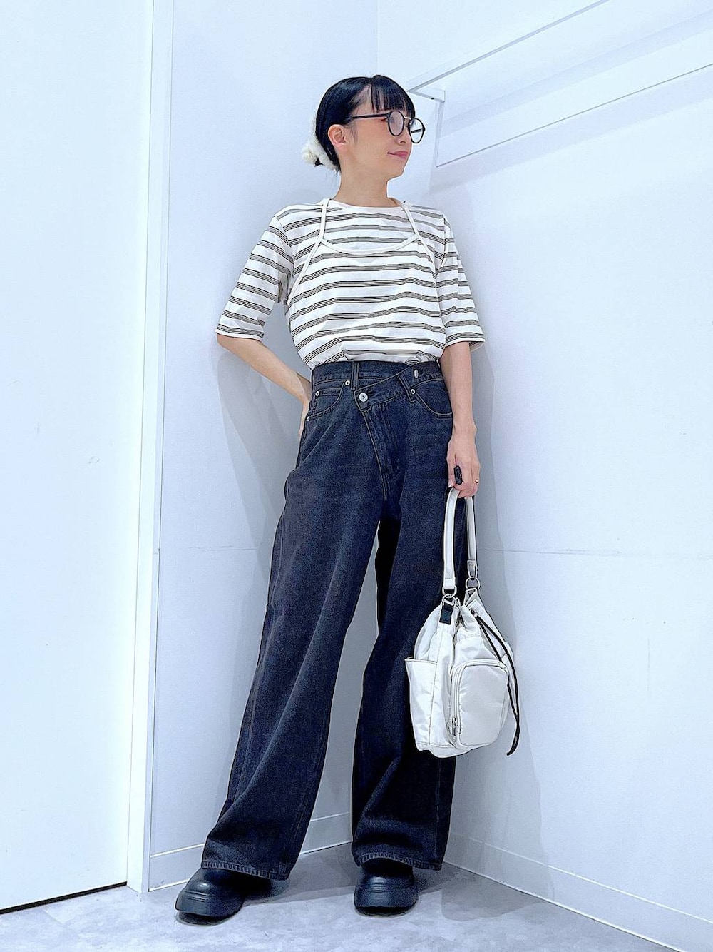ブラック系のデニムパンツ、ホワイト系のハンドバッグ、ベージュ系のTシャツ/カットソーを着用したレディースの秋コーディネートの1枚目の写真