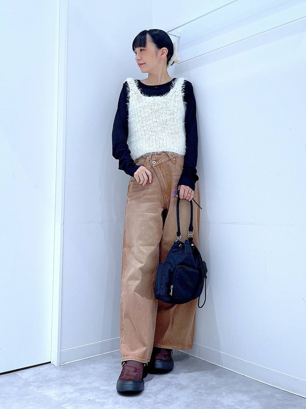 ブラウン系のデニムパンツ、ブラック系のハンドバッグ、ブラック系のTシャツ/カットソーを着用したレディースの秋コーディネートの1枚目の写真