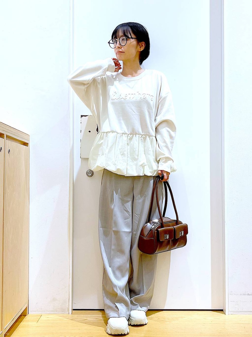 ブラウン系のハンドバッグ、ベージュ系のブーツ、ベージュ系のスウェットを着用したレディースの冬コーディネートの1枚目の写真