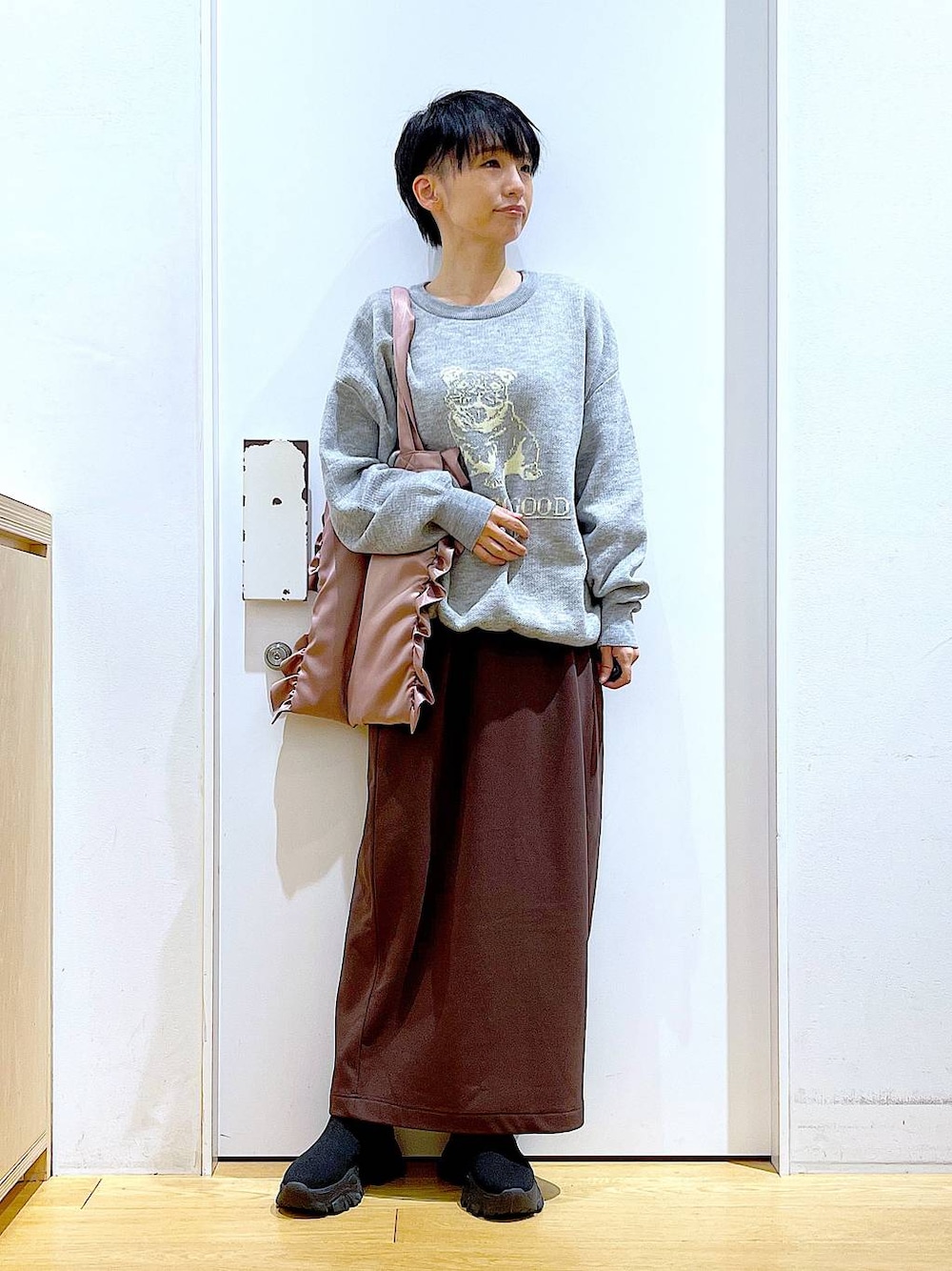 ブラック系のブーツ、ピンク系のトートバッグ、ブラウン系のスカートを着用したレディースの冬コーディネートの1枚目の写真