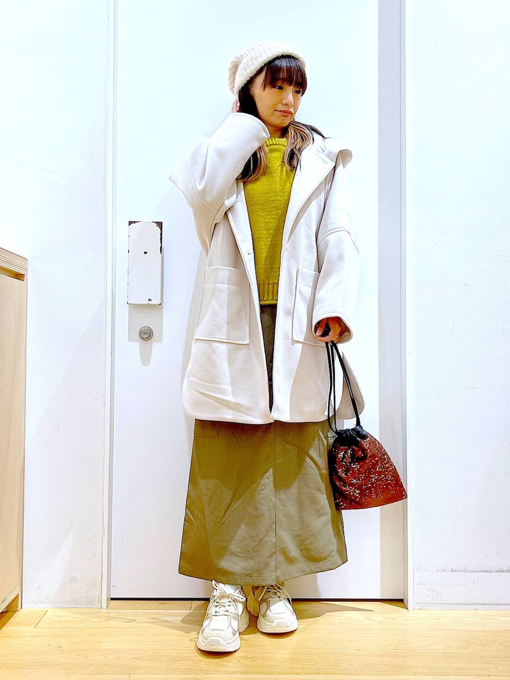 ホワイト系のその他アウター、ブラウン系のショルダーバッグ、ベージュ系のスニーカーを着用したレディースの冬コーディネートの1枚目の写真