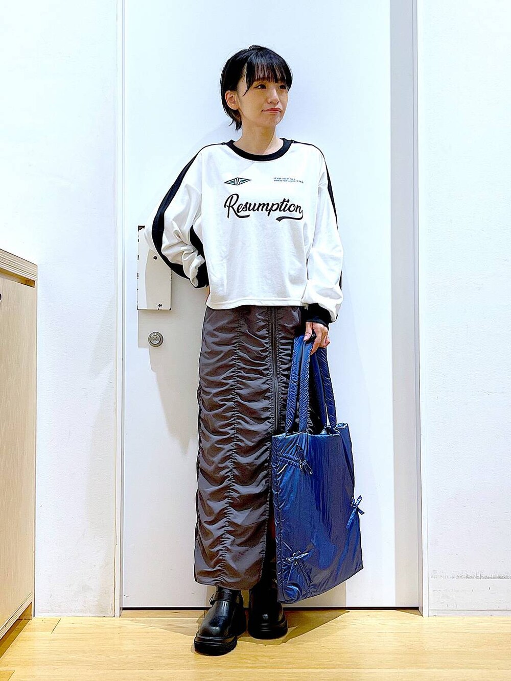 ブラック系のブーツ、ブルー系のトートバッグ、ホワイト系のTシャツ/カットソーを着用したレディースの秋コーディネートの1枚目の写真