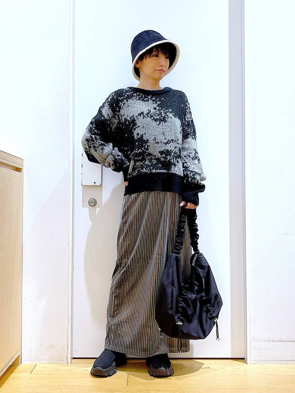 ブラック系のショルダーバッグ、グレー系のスカート、ブラック系のブーツを着用したレディースの冬コーディネートの1枚目の写真