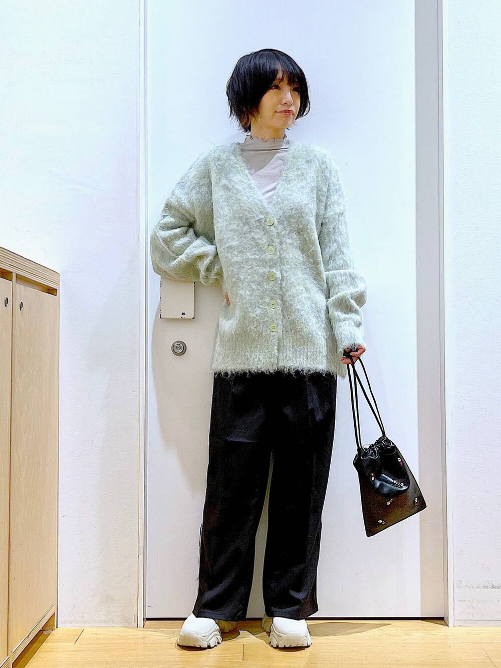 グリーン系のカーディガン/ボレロ、ブラック系のスラックス、ブラック系のショルダーバッグを着用したレディースの冬コーディネートの1枚目の写真