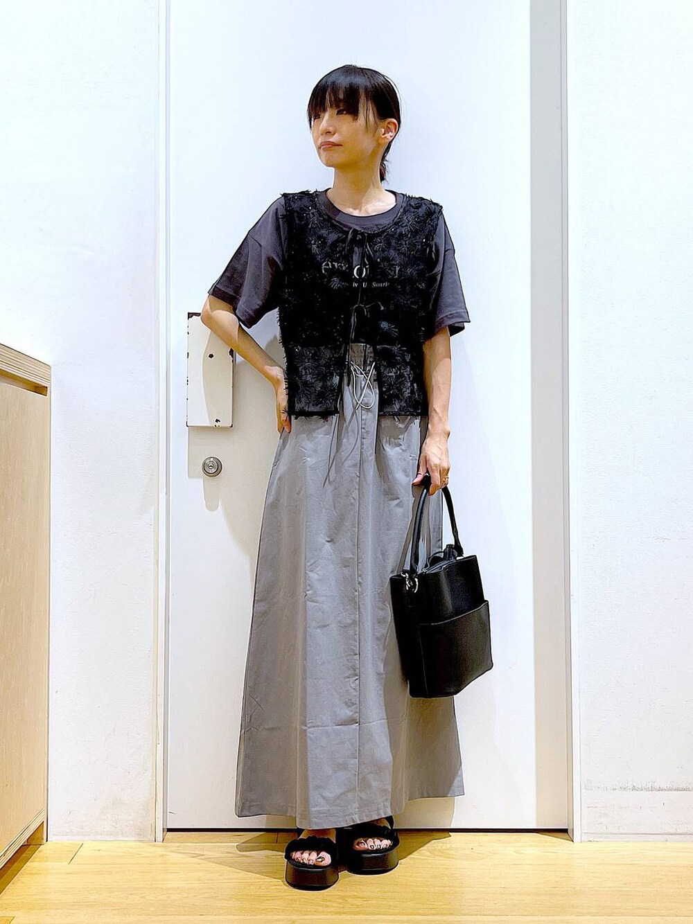 ブラック系のサンダル、ブラック系のショルダーバッグ、グレー系のスカートを着用したレディースの秋コーディネートの1枚目の写真