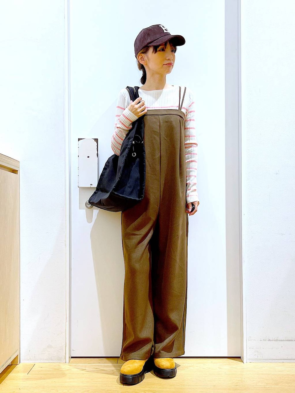 ピンク系のニット/セーター、ブラック系のショルダーバッグ、ベージュ系のブーツを着用したレディースの冬コーディネートの1枚目の写真