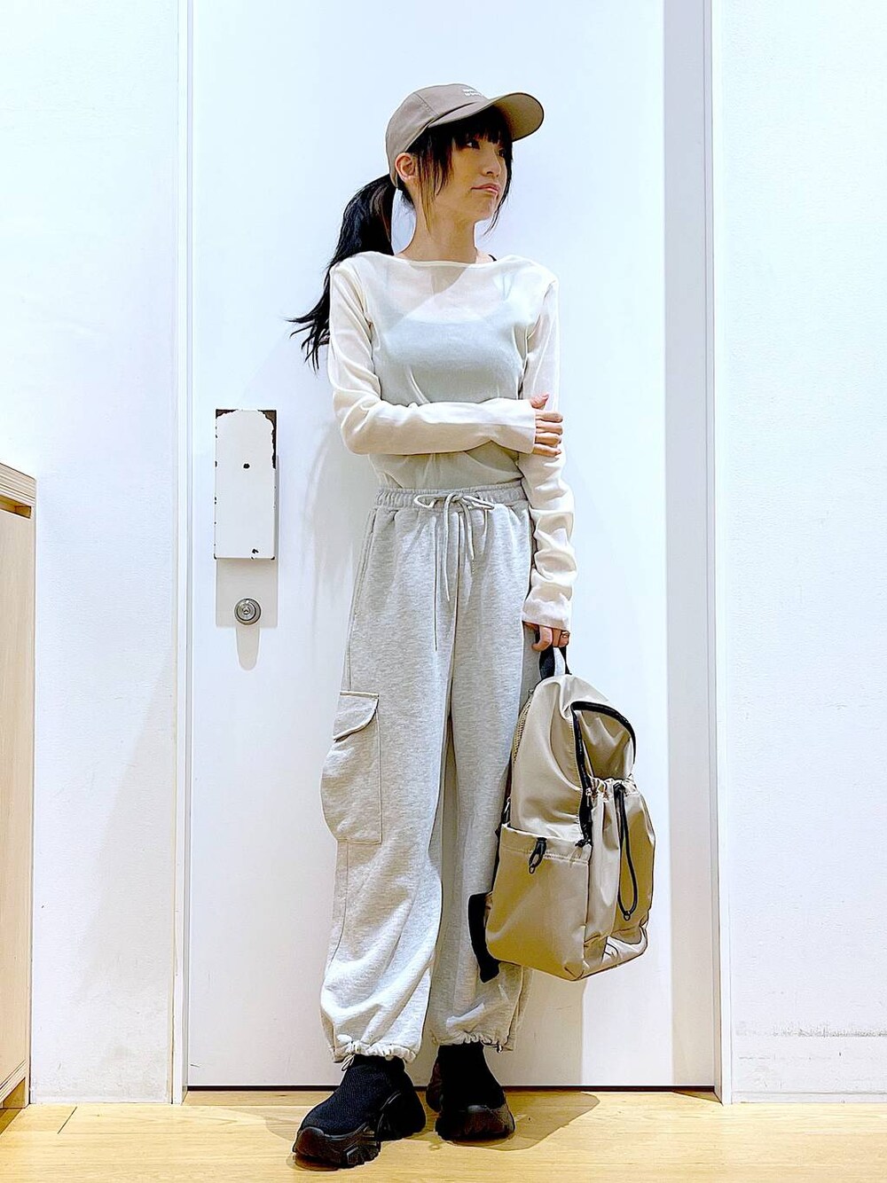 グレー系のスウェットパンツ、ベージュ系のバックパック/リュック、ブラック系のスニーカーを着用したレディースの春コーディネートの1枚目の写真