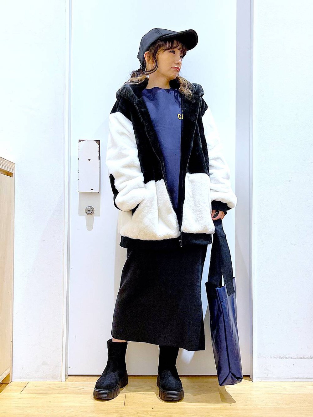 グレー系のスカート、ホワイト系のブルゾン、ブラック系のブーツを着用したレディースの冬コーディネートの1枚目の写真