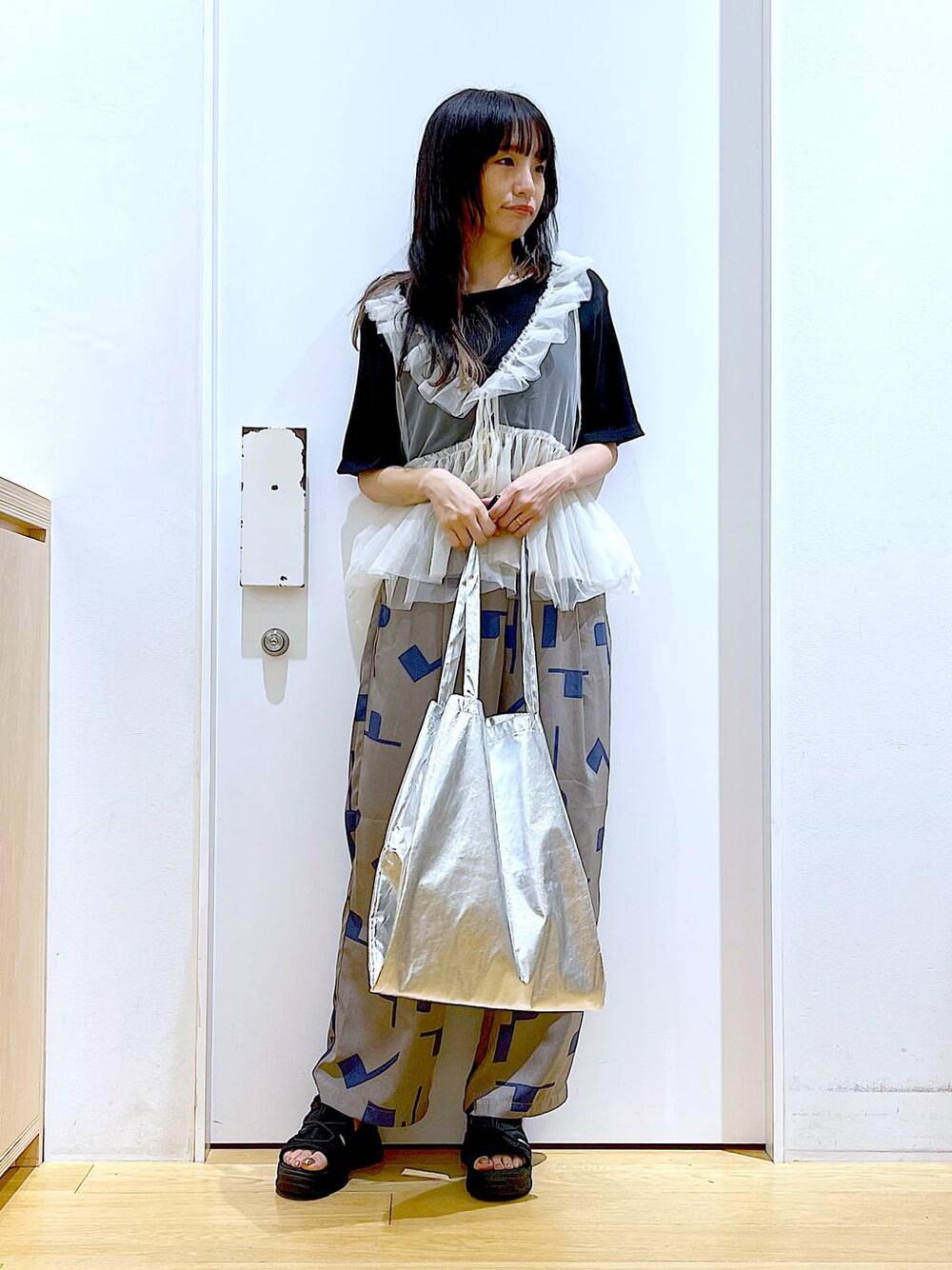 シルバー系のトートバッグ、グレー系のその他パンツ、ブラック系のサンダルを着用したレディースの夏コーディネートの1枚目の写真