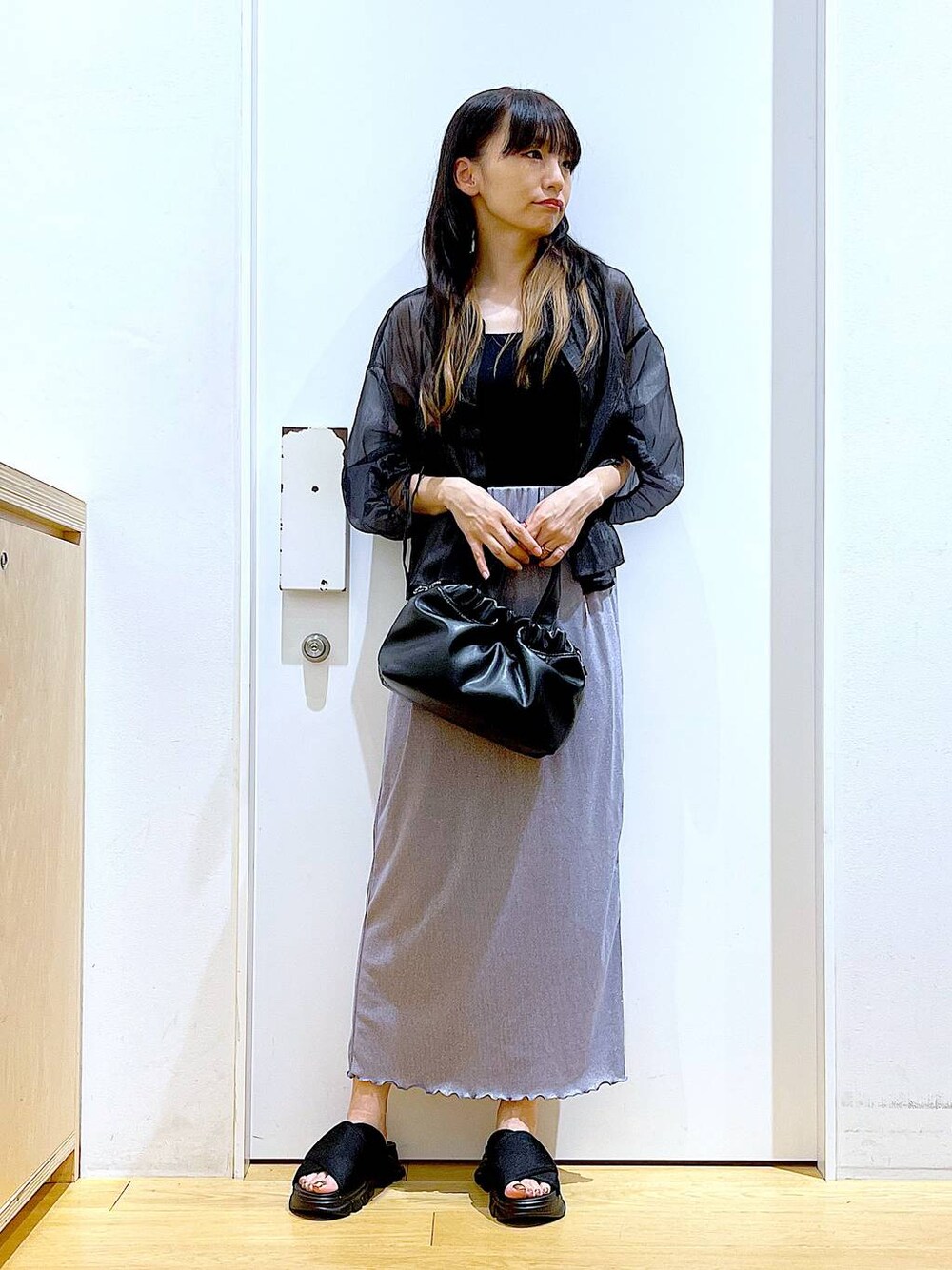 パープル系のスカート、ブラック系のサンダル、ブラック系のニット/セーターを着用したレディースの夏コーディネートの1枚目の写真