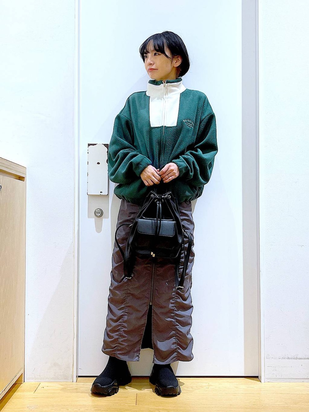 ブラック系のバックパック/リュック、グレー系のスカート、ブラック系のブーツを着用したレディースの冬コーディネートの1枚目の写真