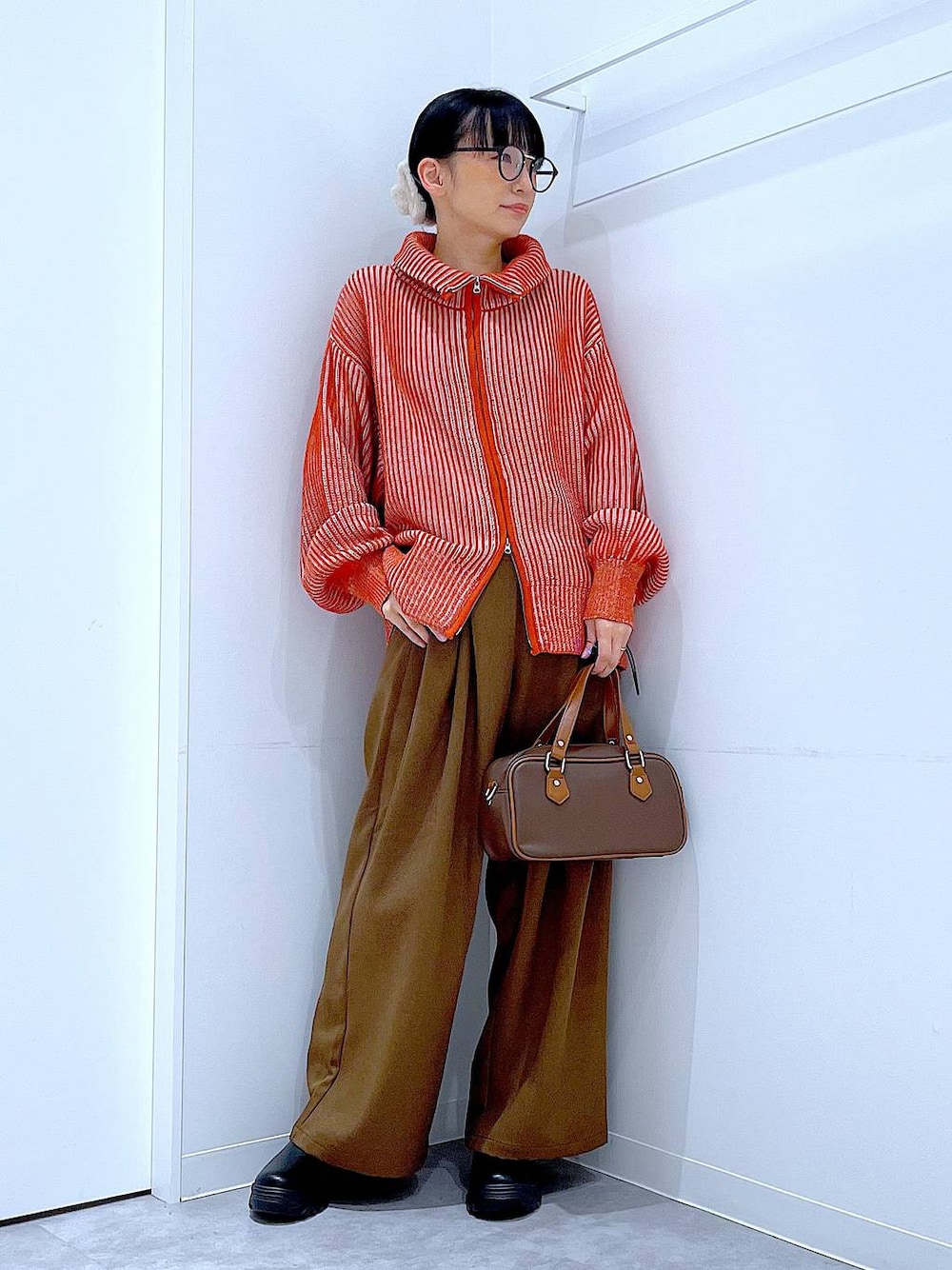 ブラック系のブーツ、オレンジ系のニット/セーター、ブラウン系のその他パンツを着用したレディースの冬コーディネートの1枚目の写真