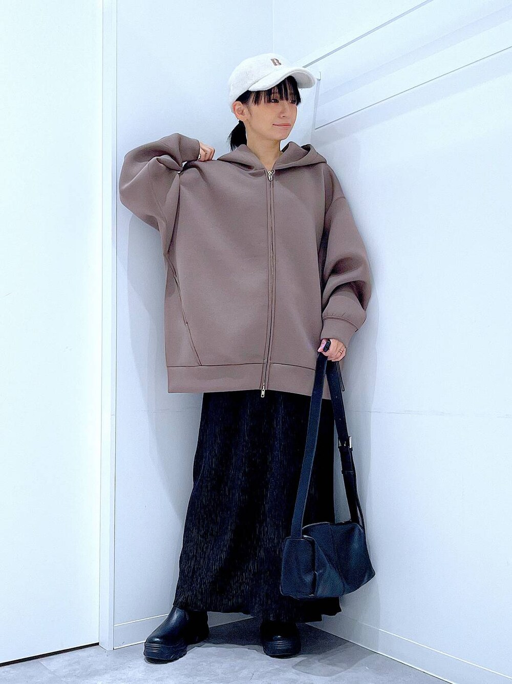 ブラック系のショルダーバッグ、ブラック系のブーツ、ブラウン系のパーカーを着用したレディースの秋コーディネートの1枚目の写真