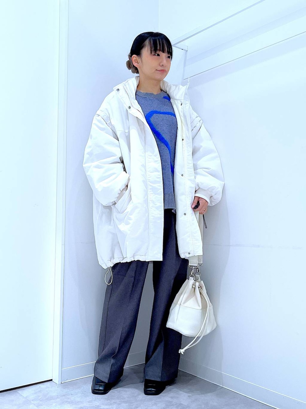 ホワイト系のブルゾン、ホワイト系のショルダーバッグ、ブラック系のブーツを着用したレディースの冬コーディネートの1枚目の写真