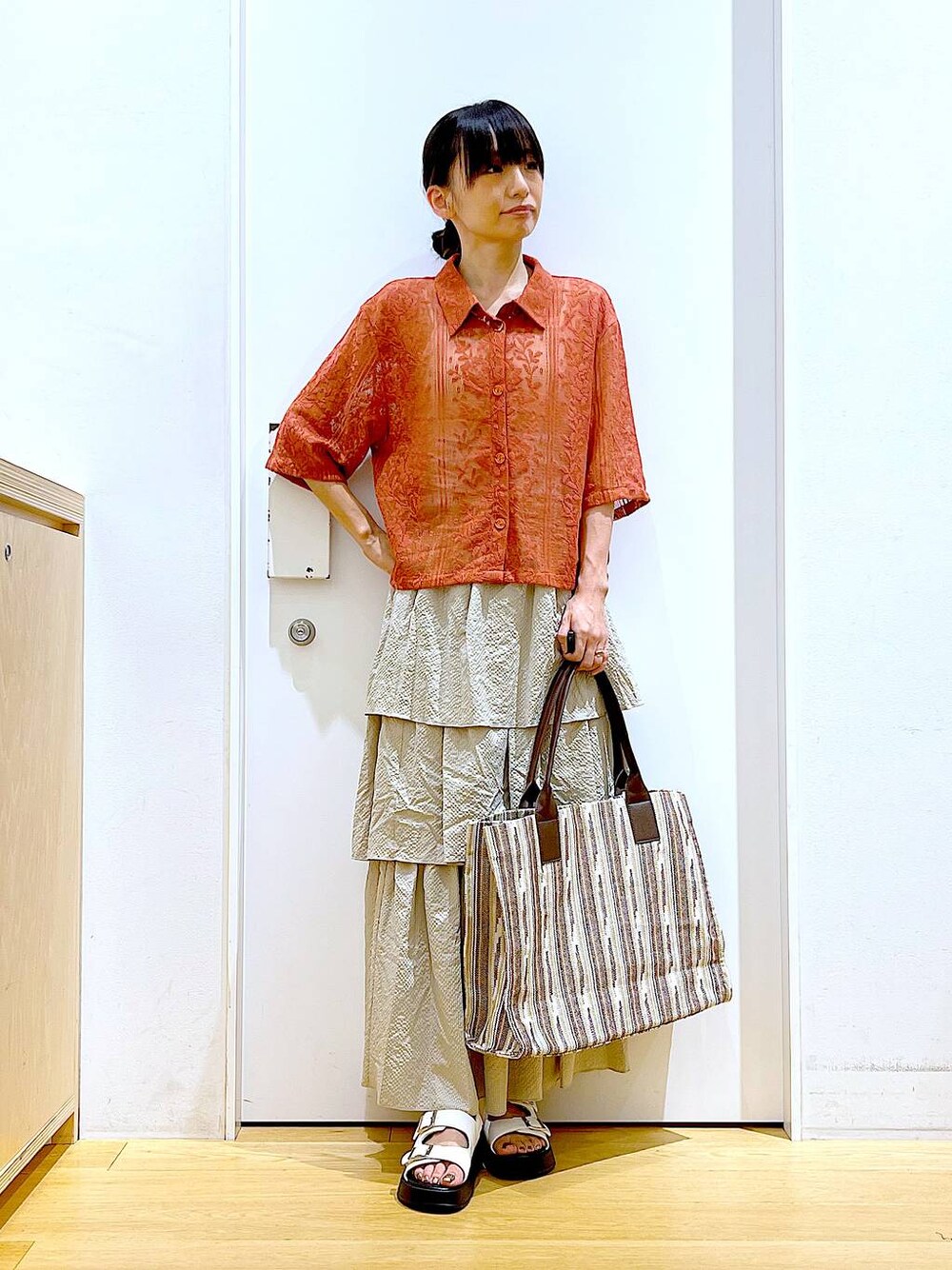 ホワイト系のサンダル、ベージュ系のスカート、レッド系のシャツ/ブラウスを着用したレディースの夏コーディネートの1枚目の写真