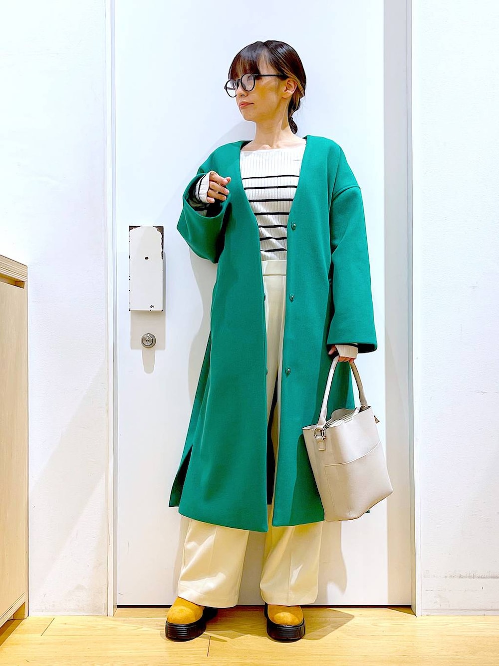 グレー系のショルダーバッグ、ホワイト系のニット/セーター、ベージュ系のブーツを着用したレディースの冬コーディネートの1枚目の写真