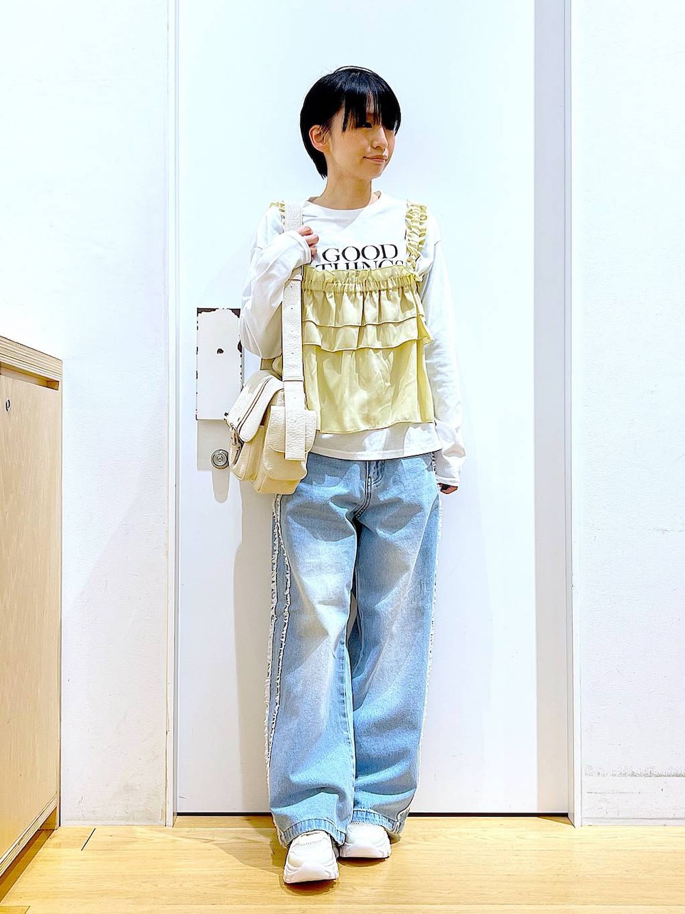ホワイト系のスニーカー、ブルー系のデニムパンツ、ベージュ系のその他トップスを着用したレディースの春コーディネートの1枚目の写真