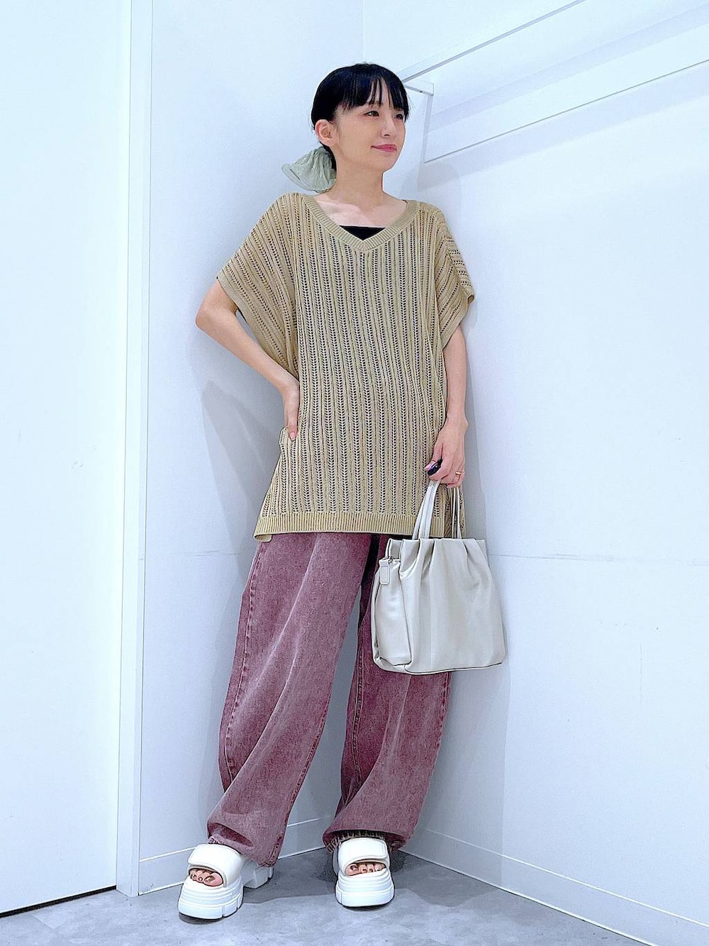 レッド系のデニムパンツ、ホワイト系のサンダル、ホワイト系のハンドバッグを着用したレディースの夏コーディネートの1枚目の写真