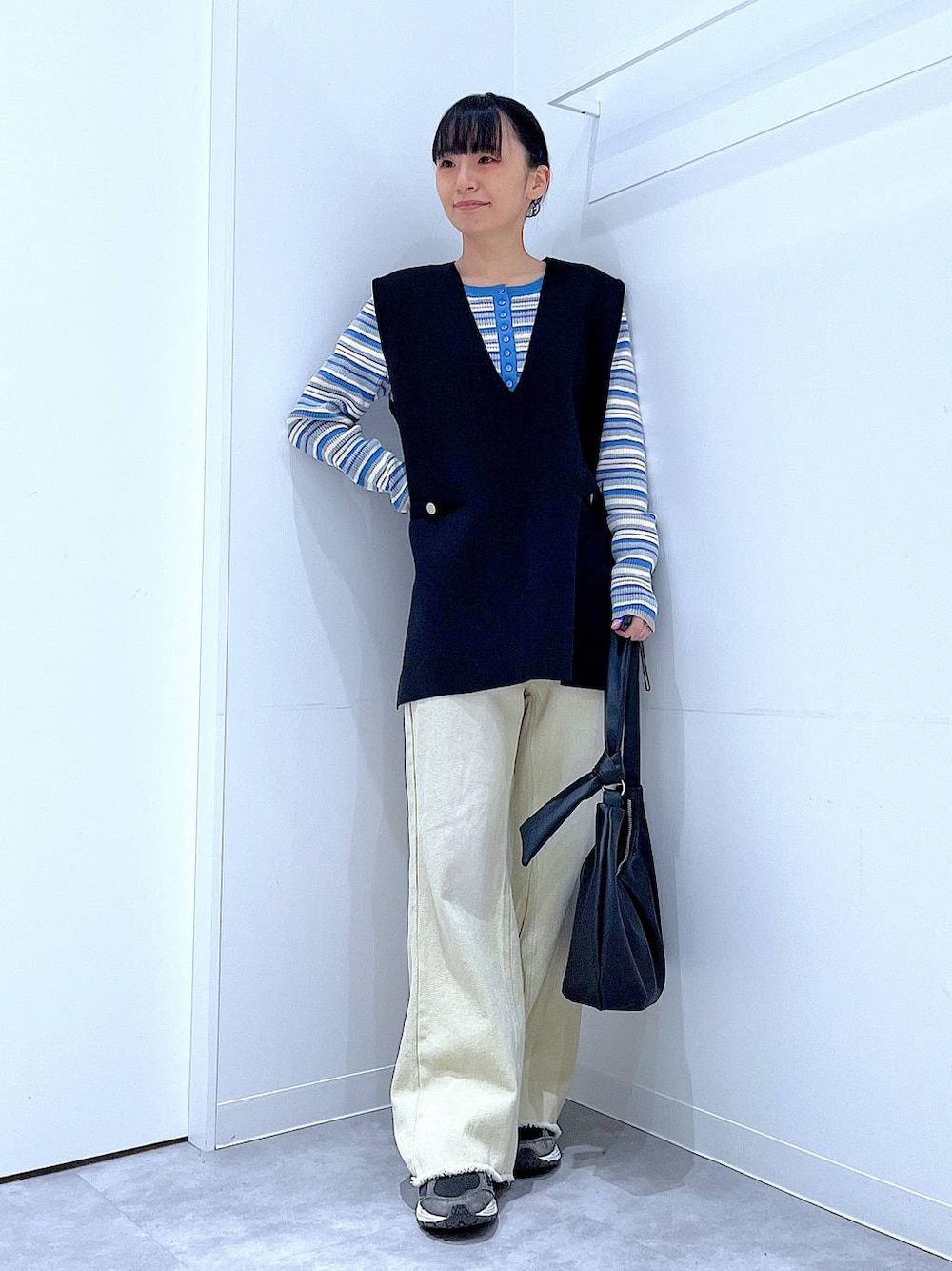 ブルー系のニット/セーター、ブラック系のベスト、ベージュ系のデニムパンツを着用したレディースの冬コーディネートの1枚目の写真