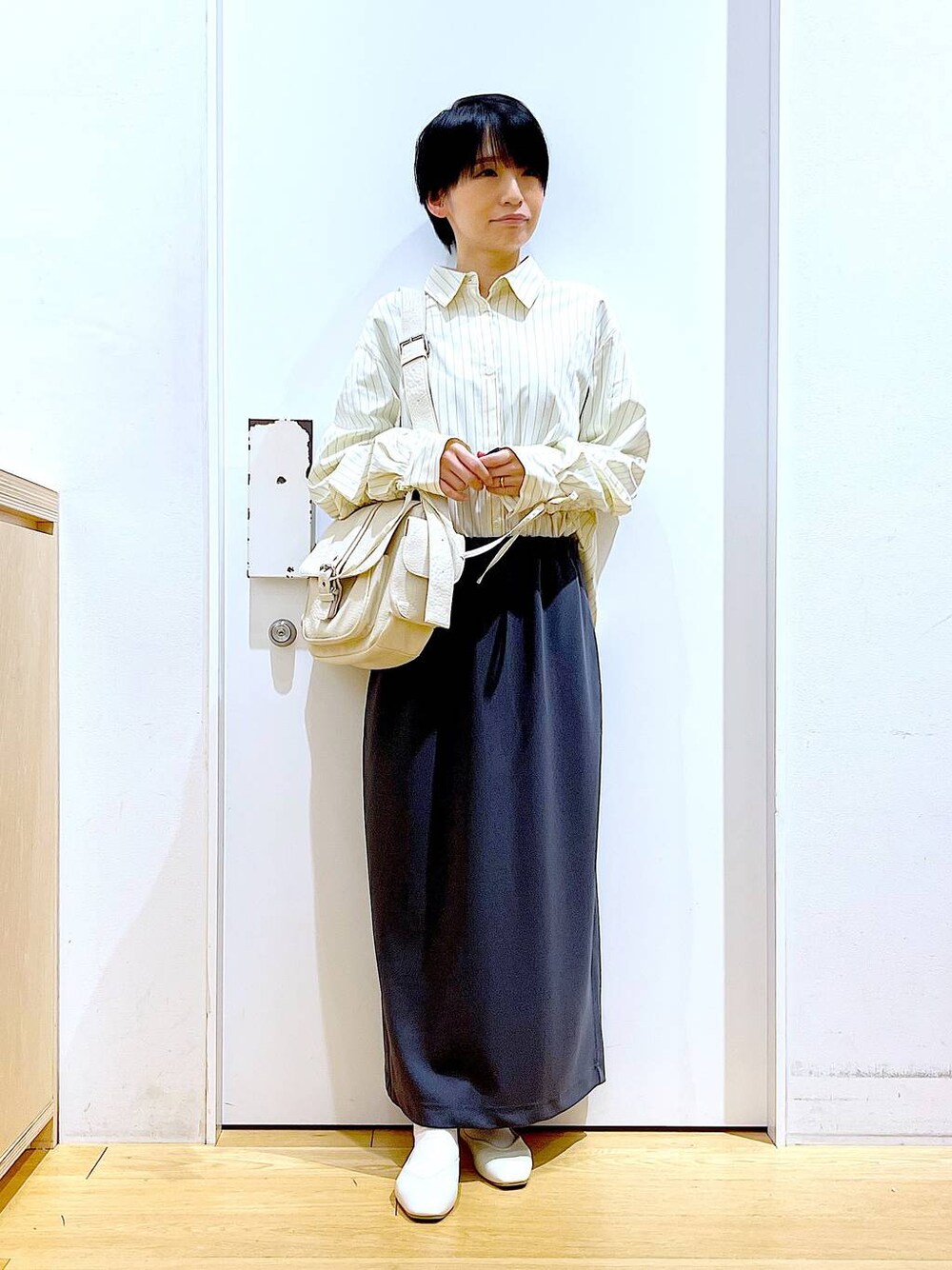 ホワイト系のパンプス、ベージュ系のシャツ/ブラウス、グレー系のスカートを着用したレディースの春コーディネートの1枚目の写真