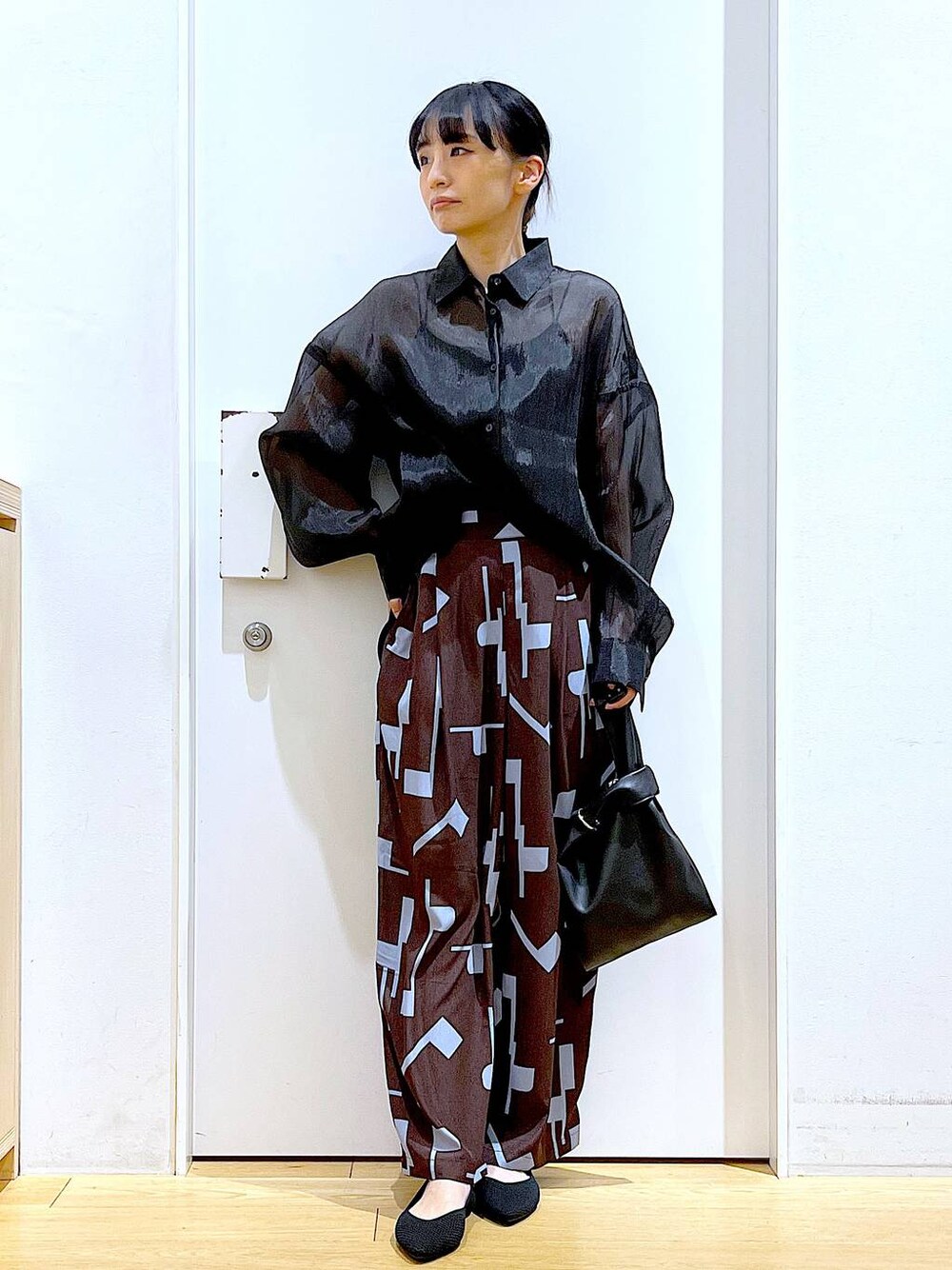 ブラック系のショルダーバッグ、ブラック系のパンプス、ブラウン系のその他パンツを着用したレディースの春コーディネートの1枚目の写真