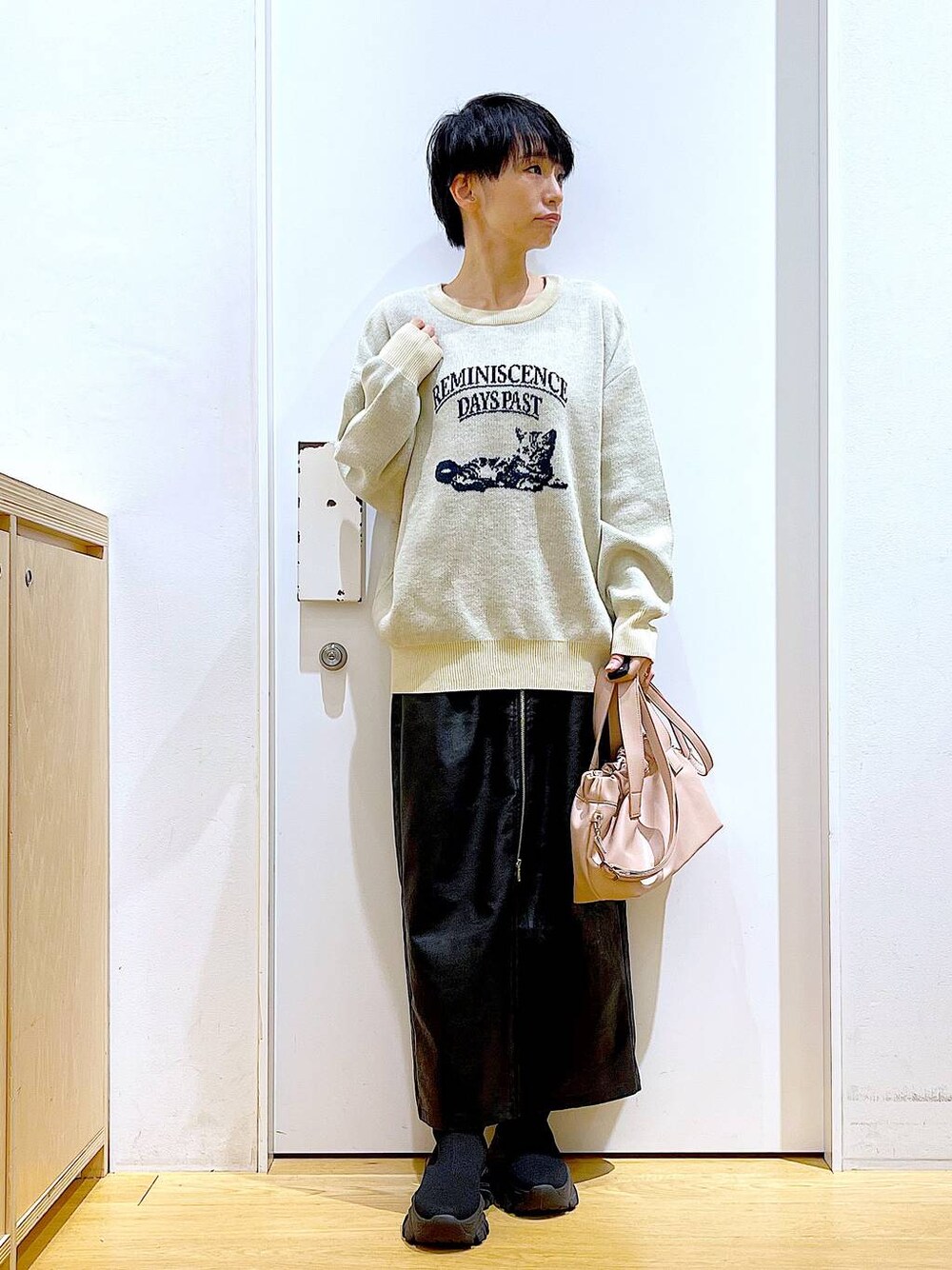 ブラック系のスカート、ブラック系のブーツ、ピンク系のショルダーバッグを着用したレディースの冬コーディネートの1枚目の写真