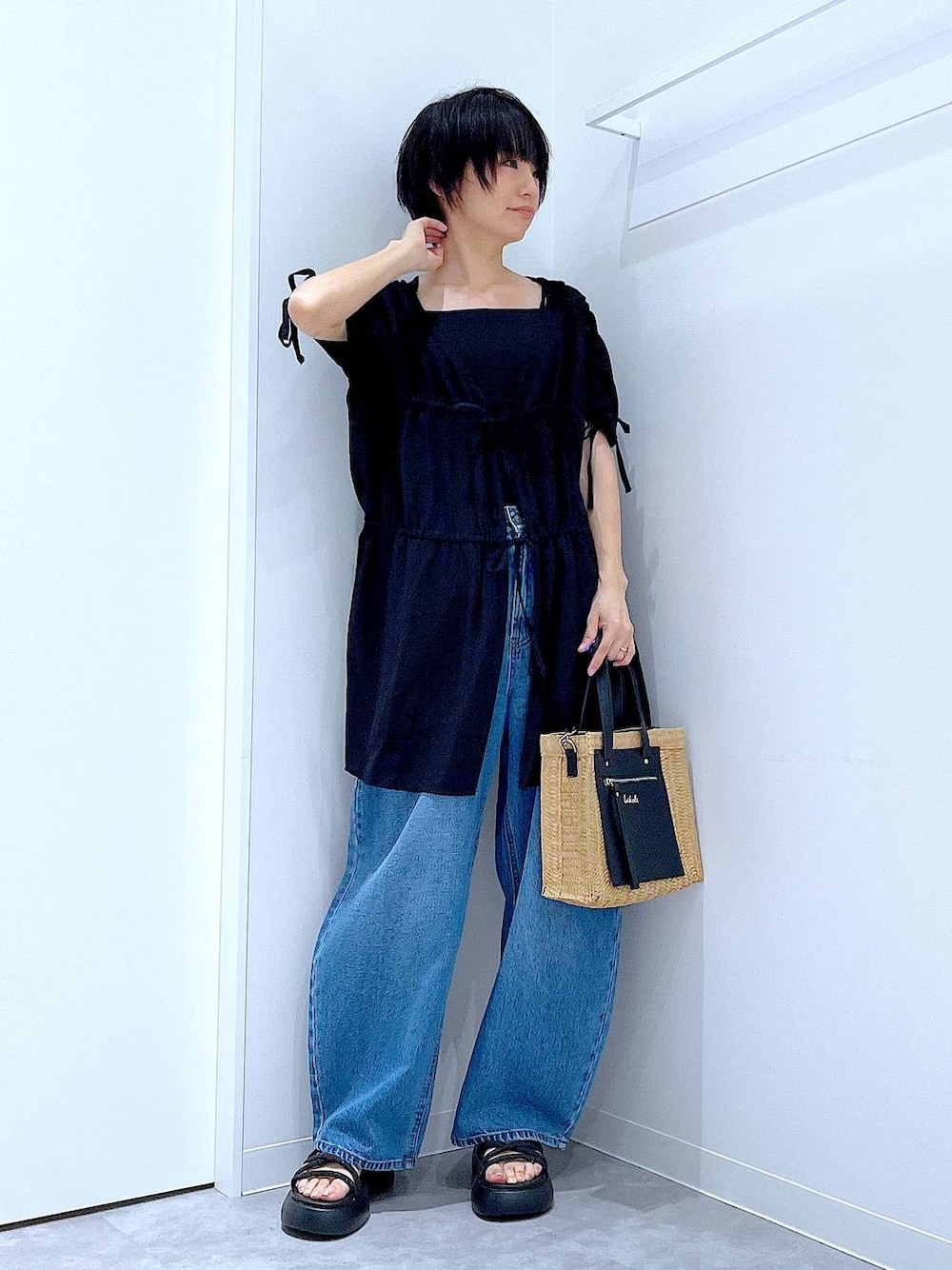 ブルー系のデニムパンツ、ベージュ系のショルダーバッグ、ブラック系のサンダルを着用したレディースの夏コーディネートの1枚目の写真