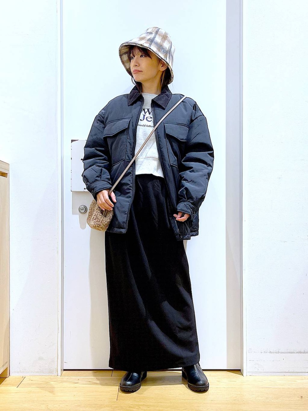 ブラック系のブルゾン、ブラック系のブーツ、ブラウン系のクラッチバッグを着用したレディースの冬コーディネートの1枚目の写真