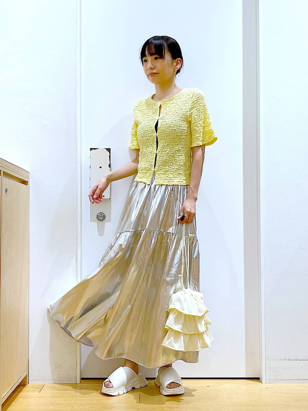ホワイト系のサンダル、シルバー系のスカート、イエロー系のカーディガン/ボレロを着用したレディースの夏コーディネートの1枚目の写真