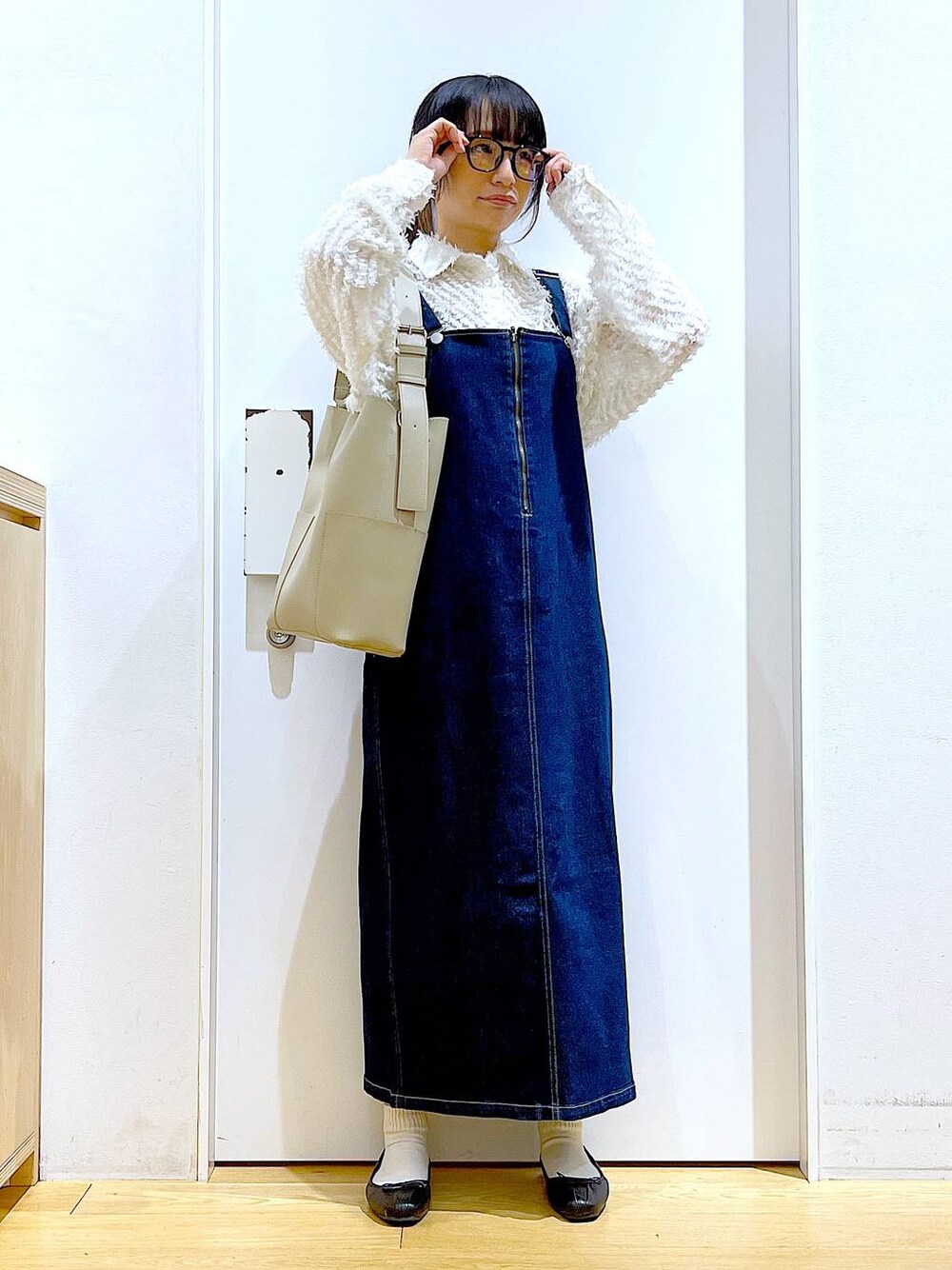 グレー系のショルダーバッグ、ブラック系のバレエシューズ、ブルー系のジャンパースカートを着用したレディースの春コーディネートの1枚目の写真