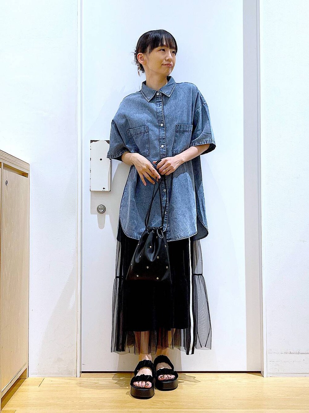 ブラック系のサンダル、ブラック系のショルダーバッグ、ブルー系のシャツ/ブラウスを着用したレディースの夏コーディネートの1枚目の写真