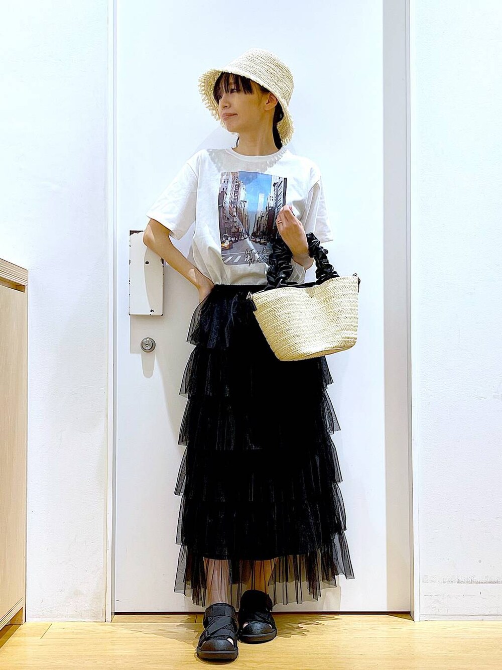 ホワイト系のショルダーバッグ、ブラック系のスリッポン、ブラック系のスカートを着用したレディースの夏コーディネートの1枚目の写真