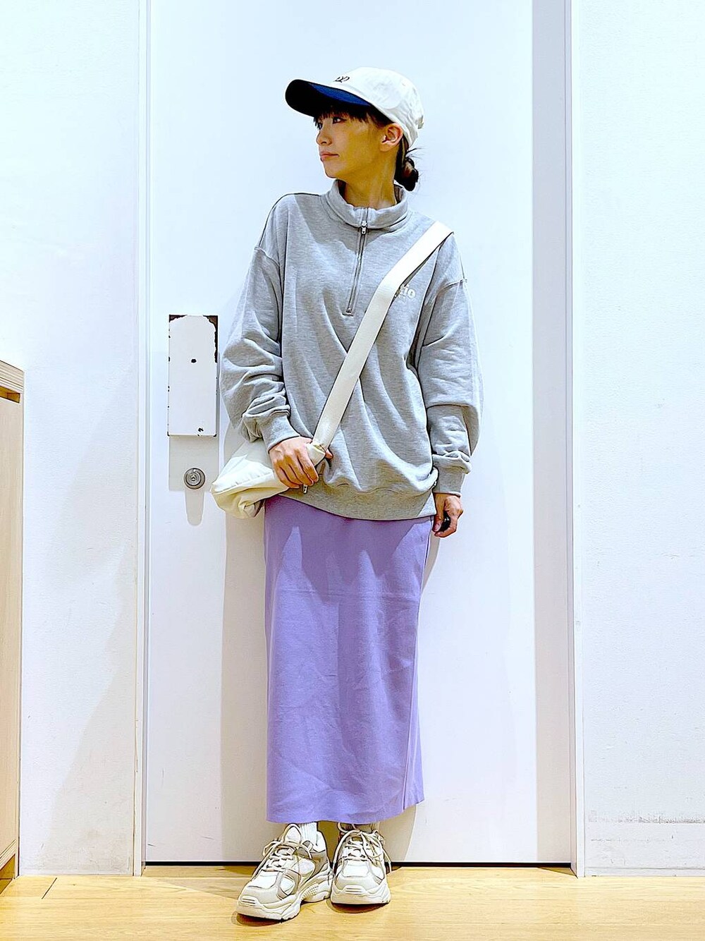 グレー系のスウェット、ベージュ系のスニーカー、ホワイト系のショルダーバッグを着用したレディースの春コーディネートの1枚目の写真