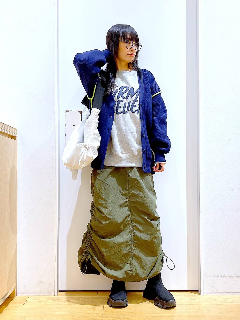 グレー系のスウェット、ブラック系のブーツ、グリーン系のスカートを着用したレディースの冬コーディネートの1枚目の写真