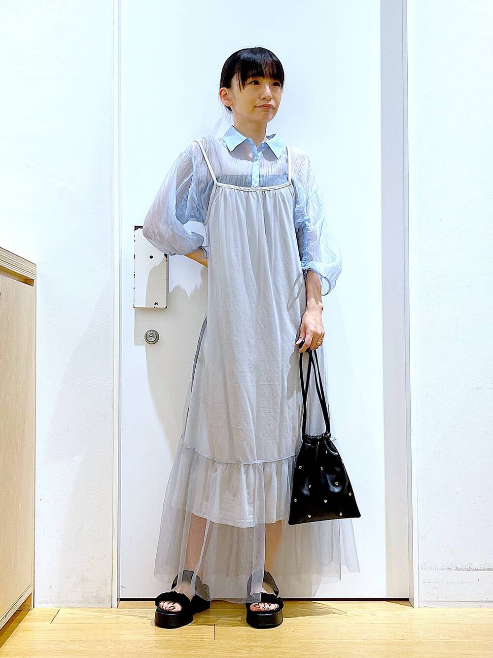 ブラック系のサンダル、ブラック系のショルダーバッグ、ブルー系のシャツ/ブラウスを着用したレディースの夏コーディネートの1枚目の写真