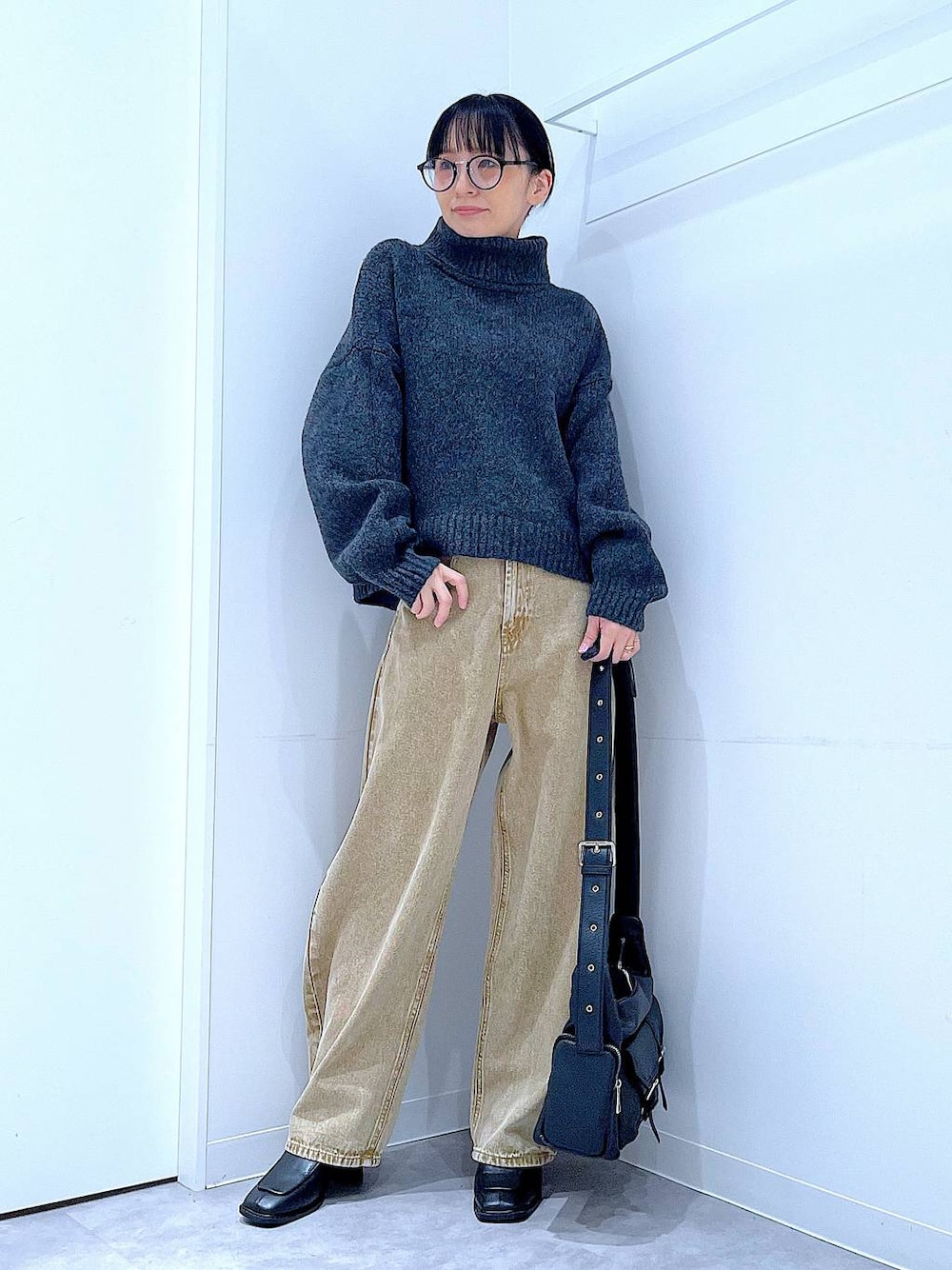 ベージュ系のデニムパンツ、ブラック系のブーツ、グレー系のニット/セーターを着用したレディースの冬コーディネートの1枚目の写真