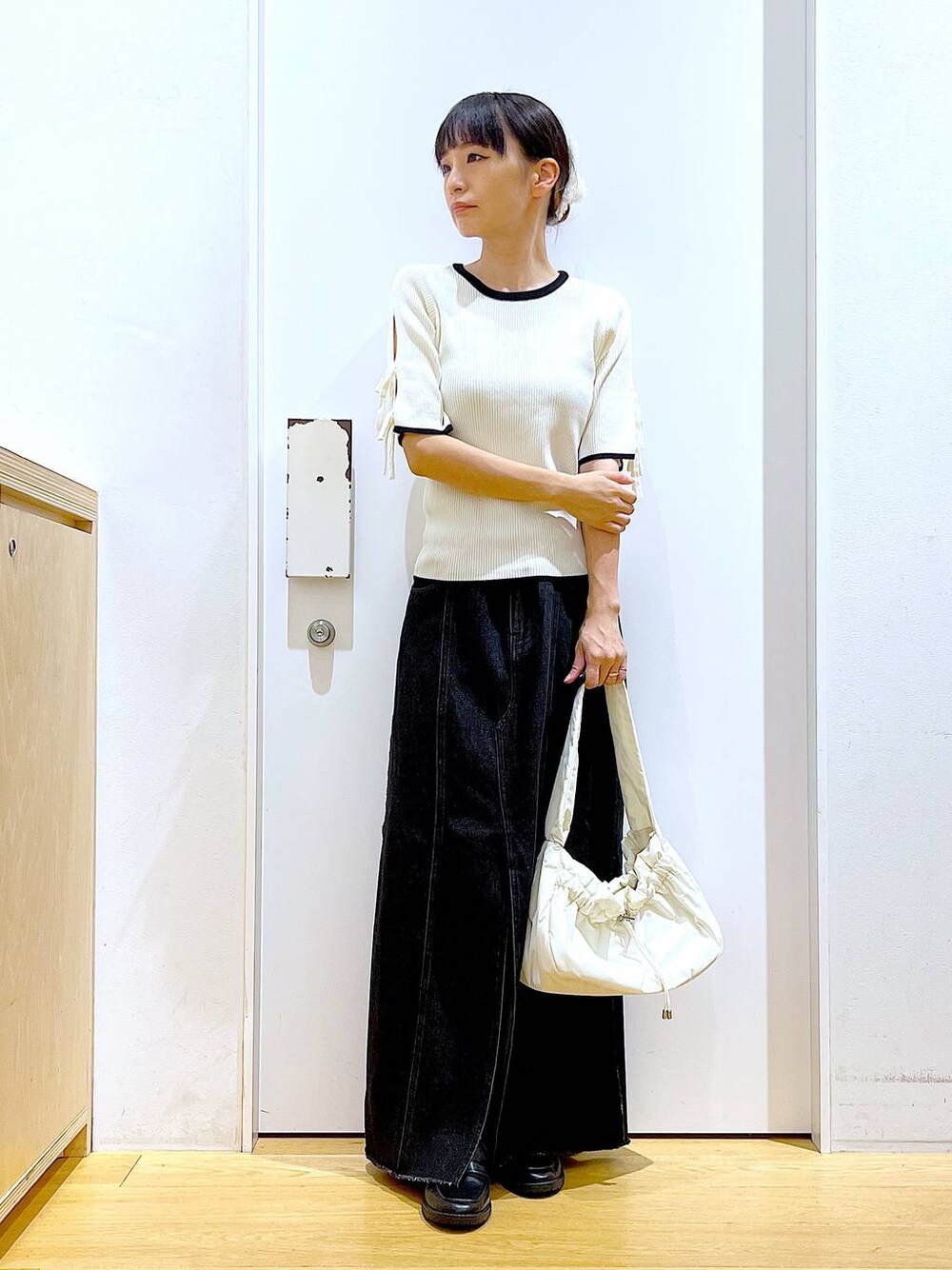 ホワイト系のハンドバッグ、ブラック系のローファー、ホワイト系のニット/セーターを着用したレディースの秋コーディネートの1枚目の写真