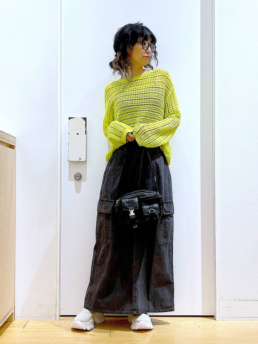 グレー系のデニムスカート、ベージュ系のスニーカー、ブラック系のショルダーバッグを着用したレディースの春コーディネートの1枚目の写真