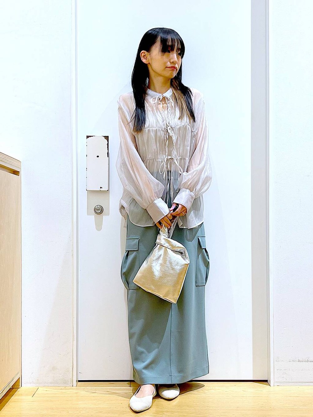 シルバー系のショルダーバッグ、グレー系のシャツ/ブラウス、ホワイト系のパンプスを着用したレディースの春コーディネートの1枚目の写真