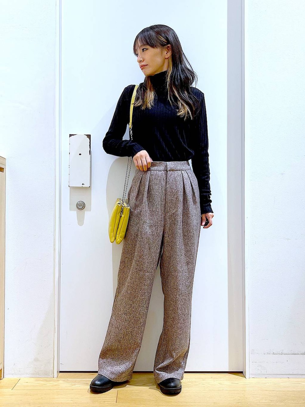 イエロー系のショルダーバッグ、ブラック系のブーツ、ブラウン系のその他パンツを着用したレディースの冬コーディネートの1枚目の写真