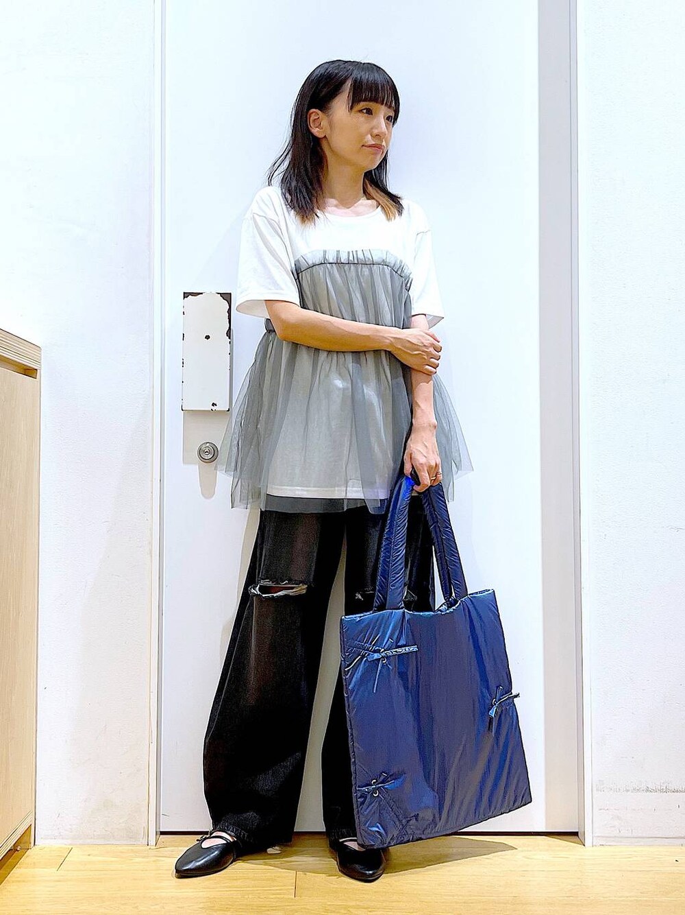 グレー系のTシャツ/カットソー、ブラック系のデニムパンツ、ブルー系のトートバッグを着用したレディースの秋コーディネートの1枚目の写真