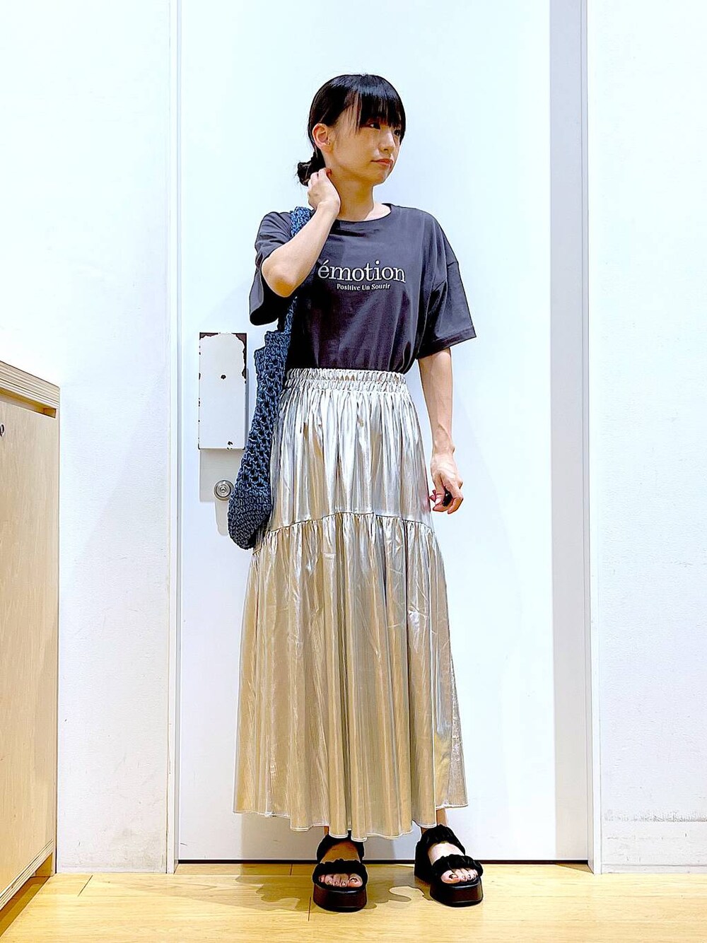 ブラック系のサンダル、シルバー系のスカート、ブルー系のトートバッグを着用したレディースの夏コーディネートの1枚目の写真