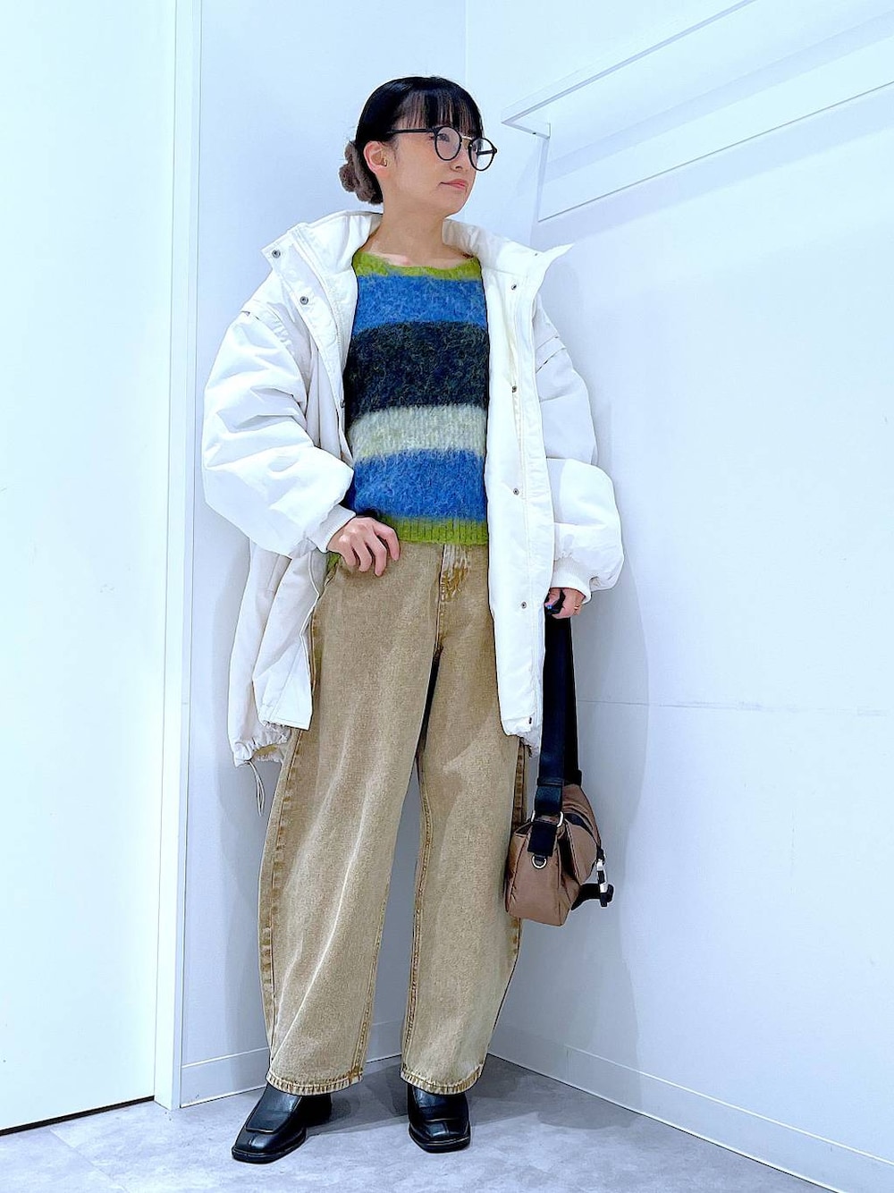 ベージュ系のデニムパンツ、ホワイト系のブルゾン、ブラック系のブーツを着用したレディースの冬コーディネートの1枚目の写真