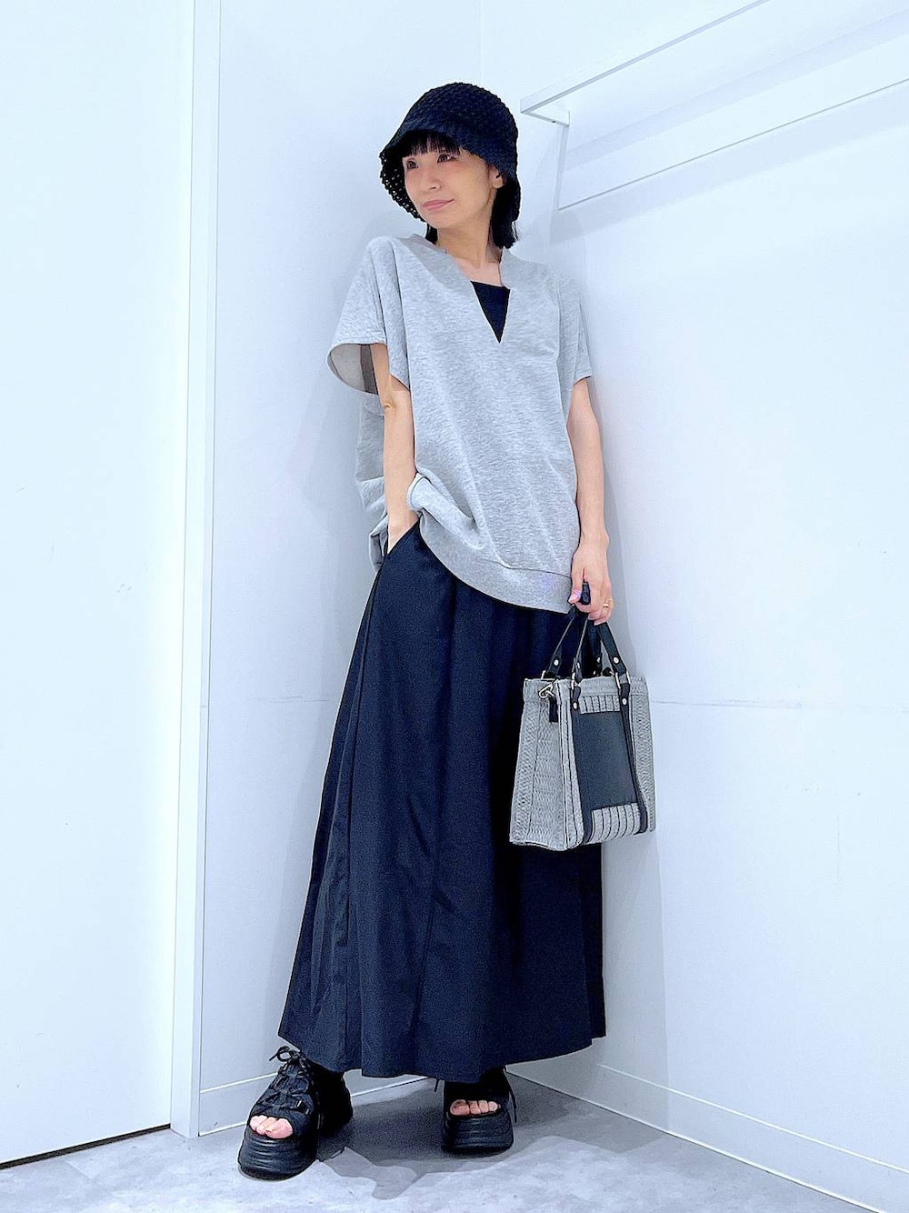 グレー系のショルダーバッグ、ブラック系のサンダル、グレー系のTシャツ/カットソーを着用したレディースの夏コーディネートの1枚目の写真