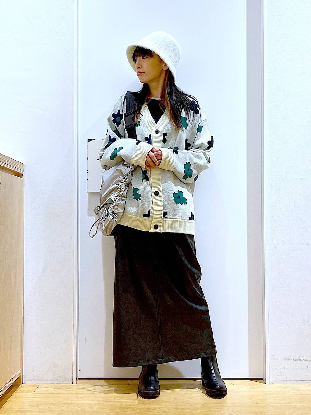 ベージュ系のカーディガン/ボレロ、ブラック系のブーツ、ブラック系のニット/セーターを着用したレディースの冬コーディネートの1枚目の写真