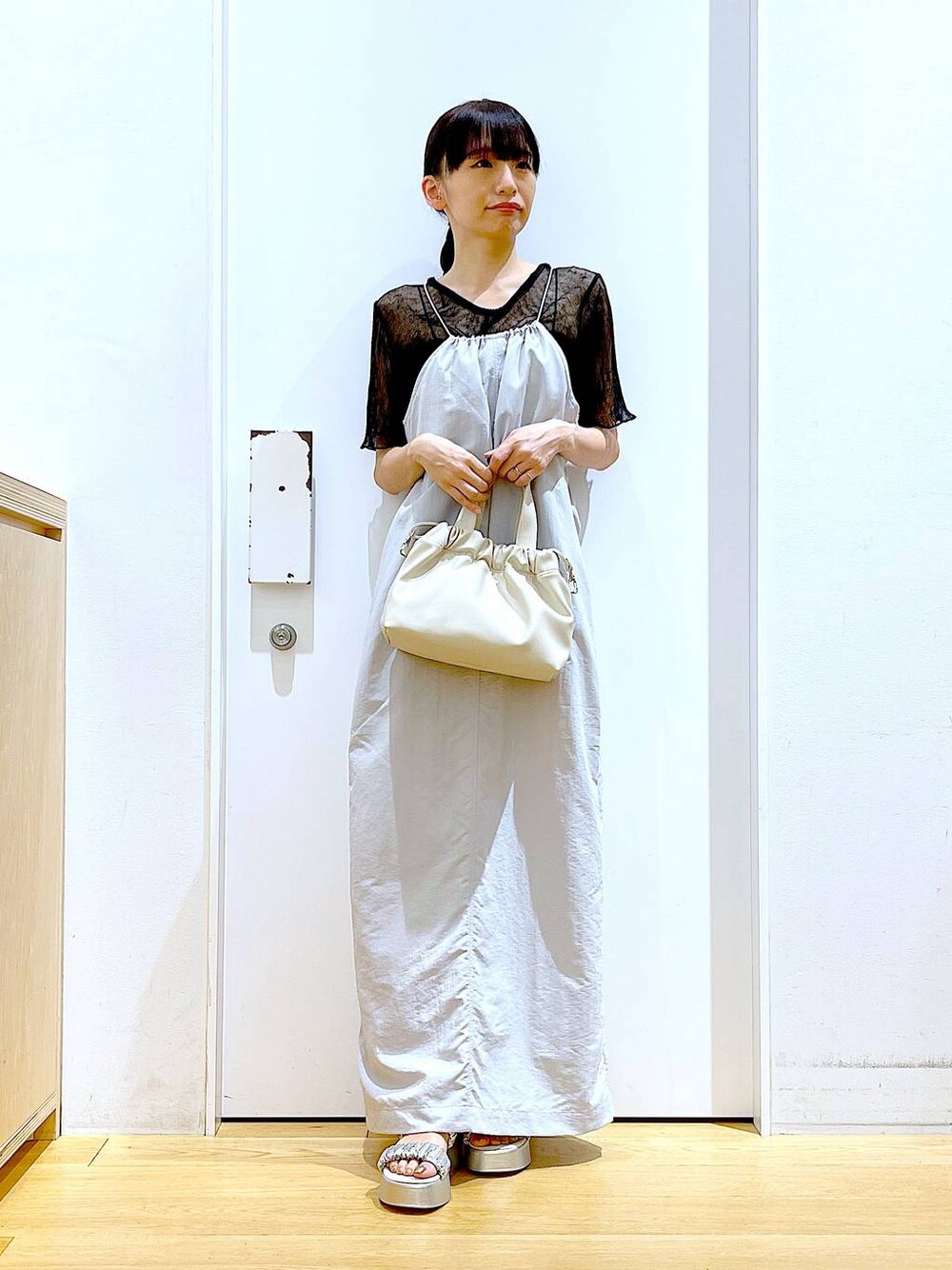 グレー系のワンピース、ホワイト系のショルダーバッグ、シルバー系のサンダルを着用したレディースの夏コーディネートの1枚目の写真