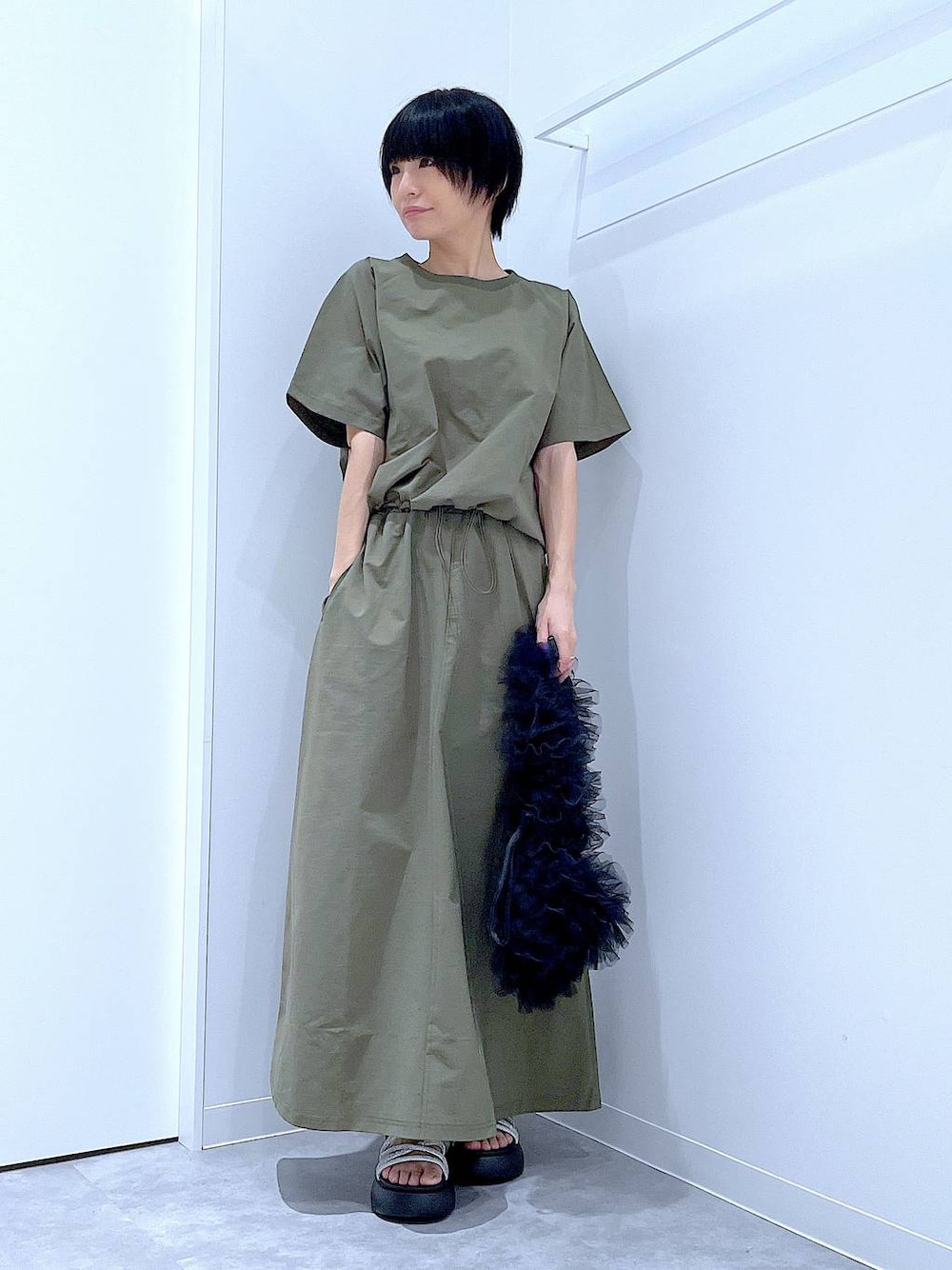 ブラック系のショルダーバッグ、シルバー系のサンダル、グリーン系のTシャツ/カットソーを着用したレディースの夏コーディネートの1枚目の写真