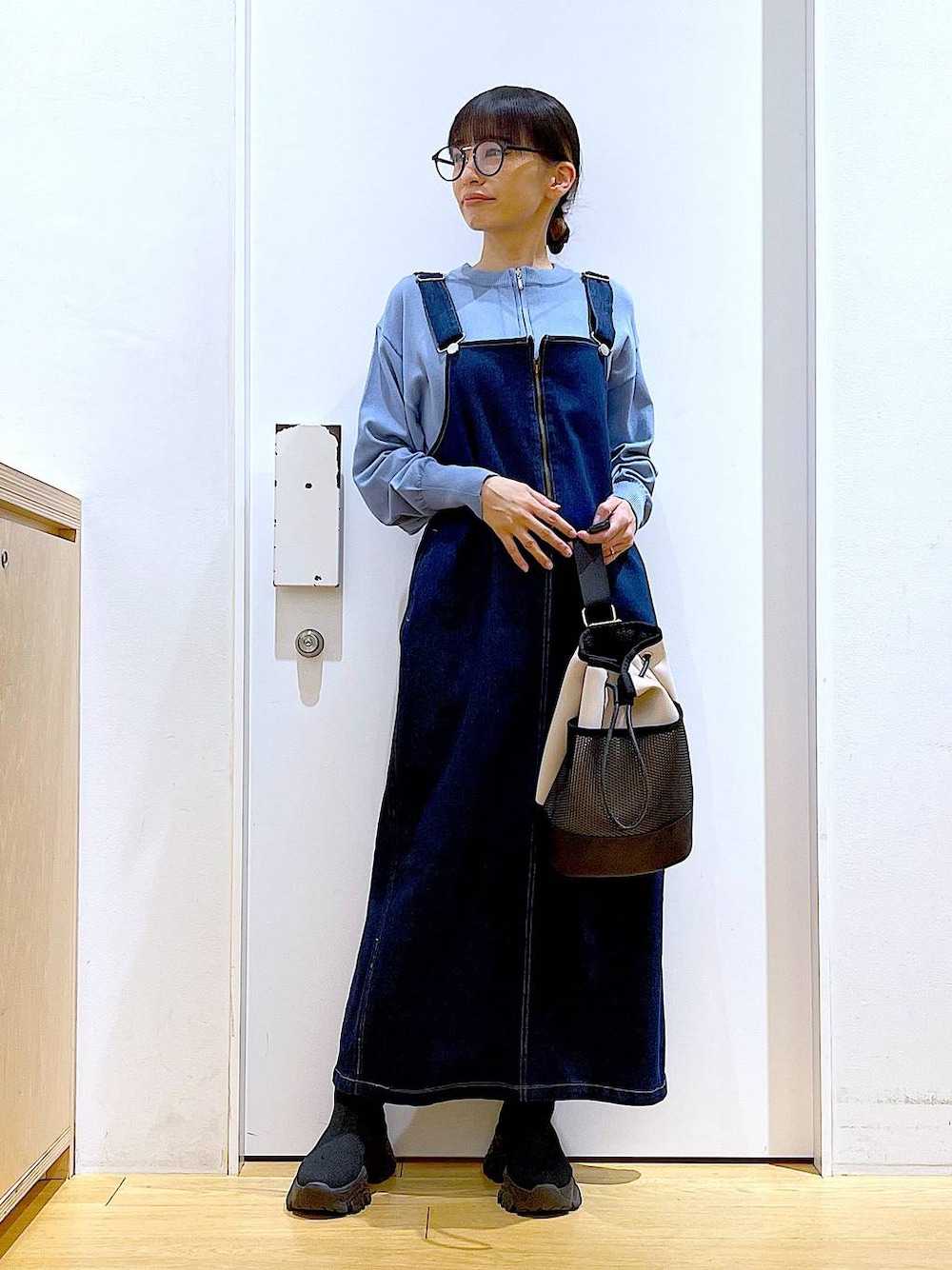 ブルー系のジャンパースカート、ブルー系のカーディガン/ボレロ、ブラック系のブーツを着用したレディースの春コーディネートの1枚目の写真