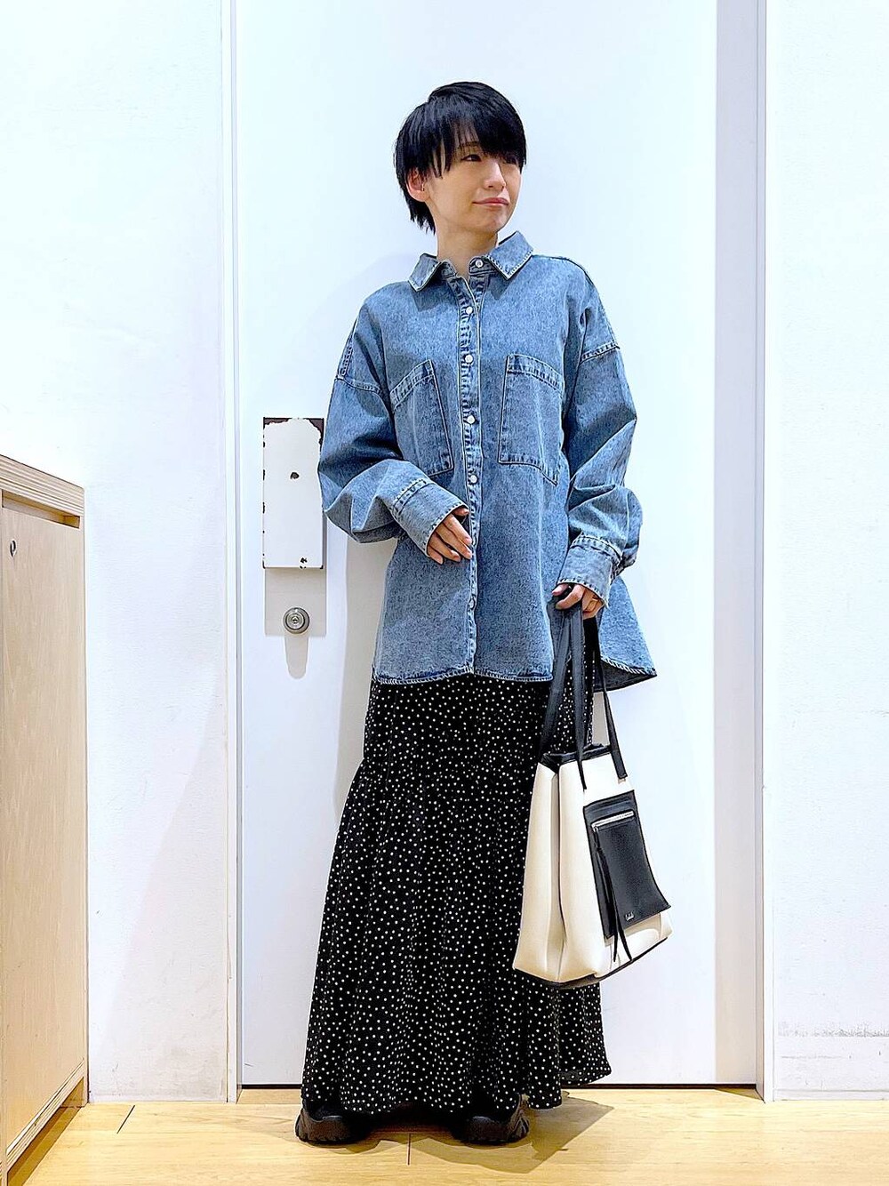 ブラック系のブーツ、ブルー系のシャツ/ブラウス、ホワイト系のトートバッグを着用したレディースの春コーディネートの1枚目の写真