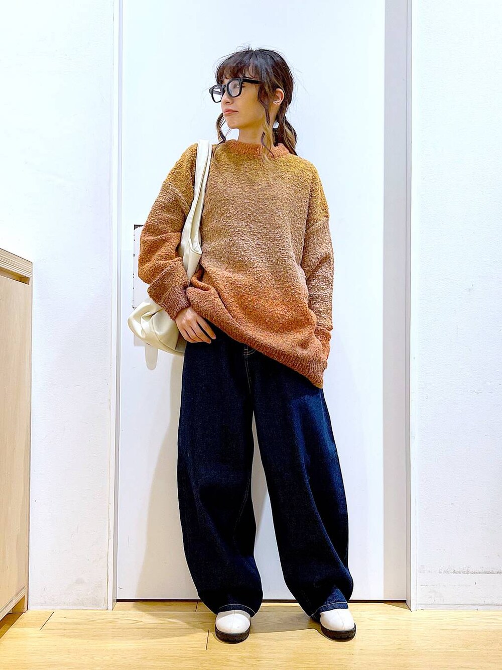 オレンジ系のニット/セーター、ホワイト系のトートバッグ、ベージュ系のブーツを着用したレディースの冬コーディネートの1枚目の写真